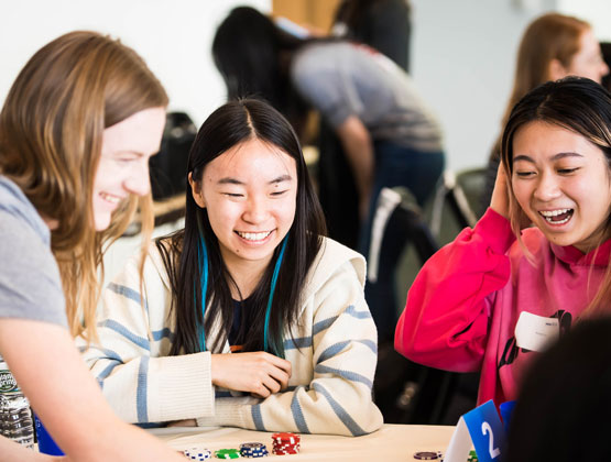 three women laughing playing poker